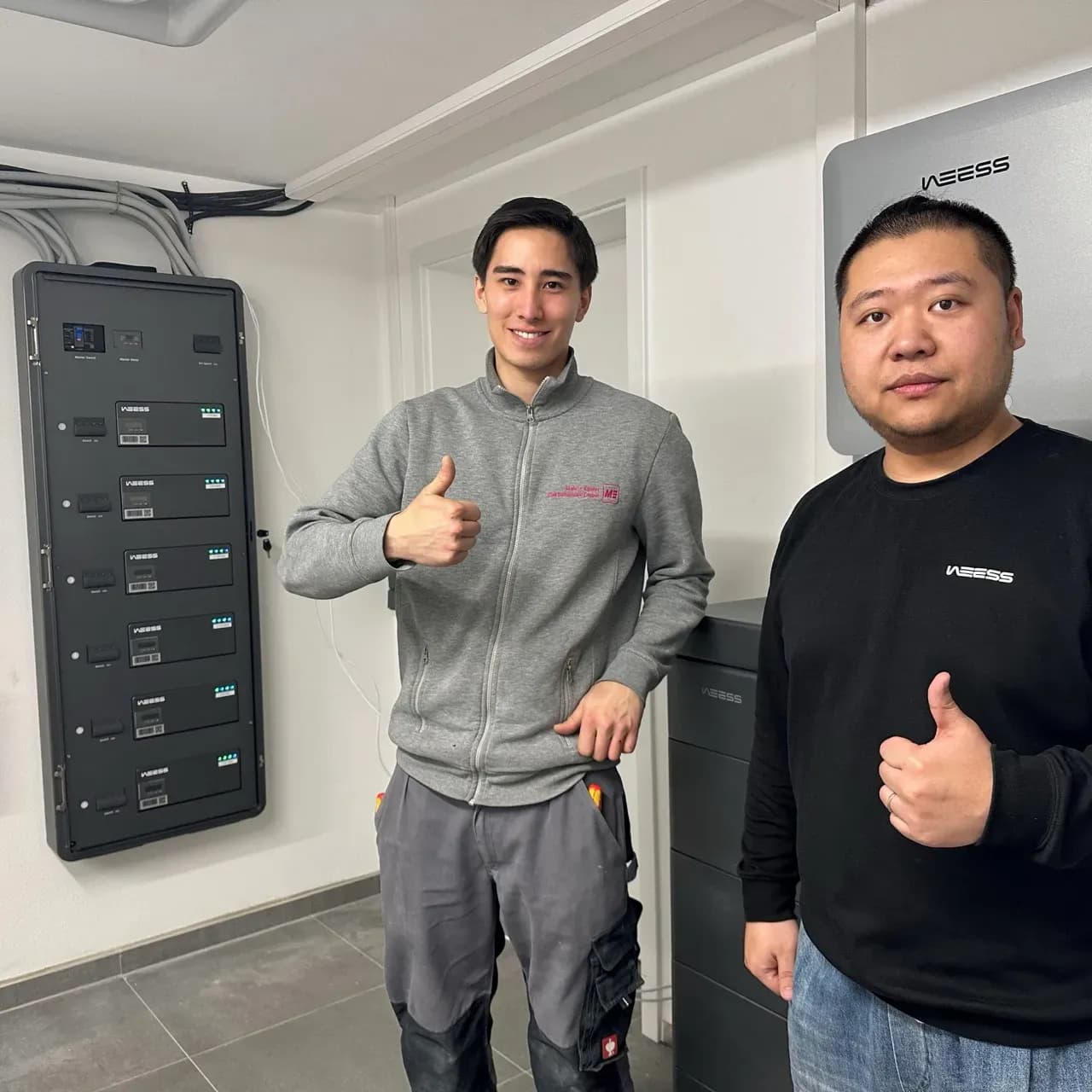 Installateur und WEESS Techniker vor installierter Energieverteilungsanlage im Technikraum