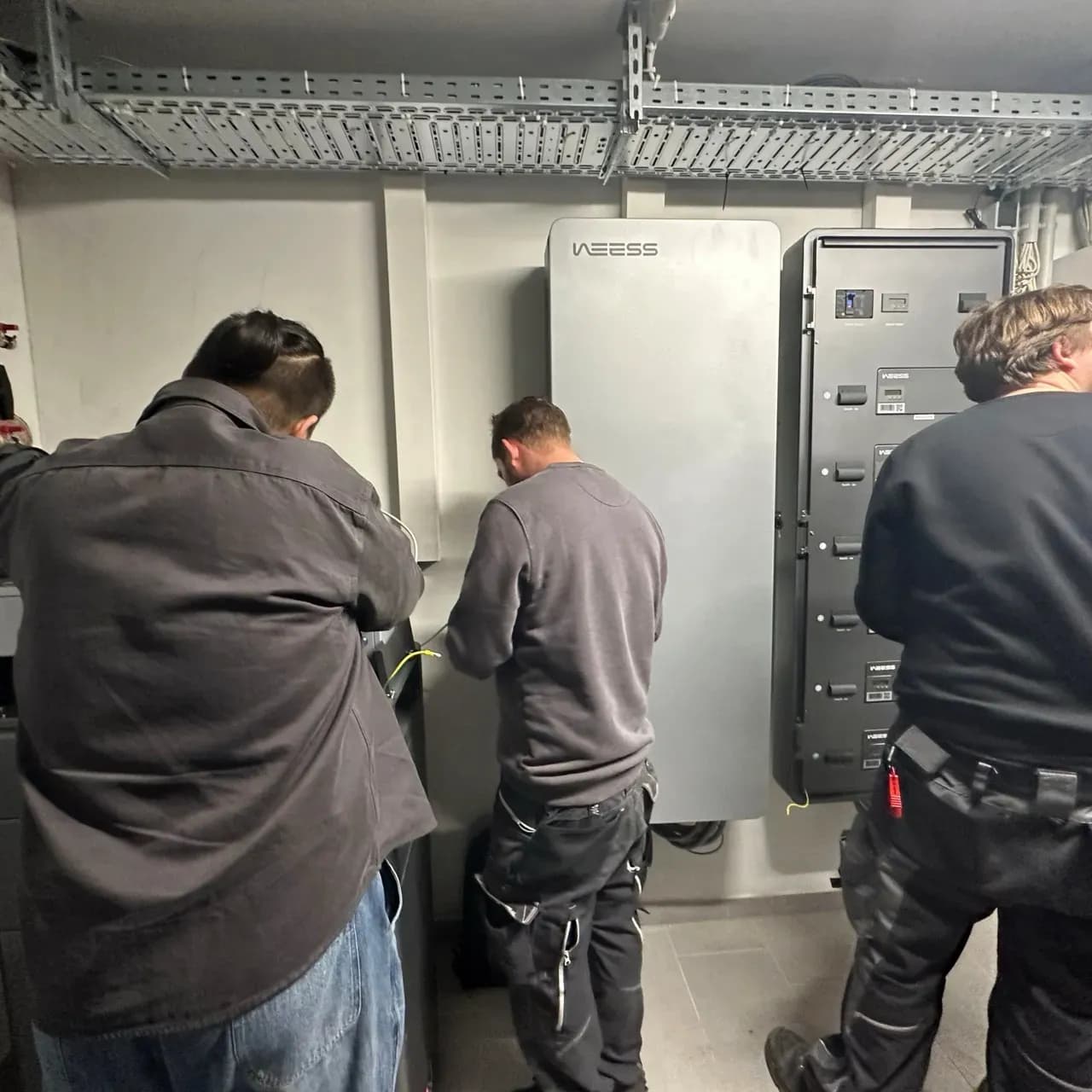 Techniker installieren WEESS Energiespeicher und Energieverteilungssystem im Technikraum