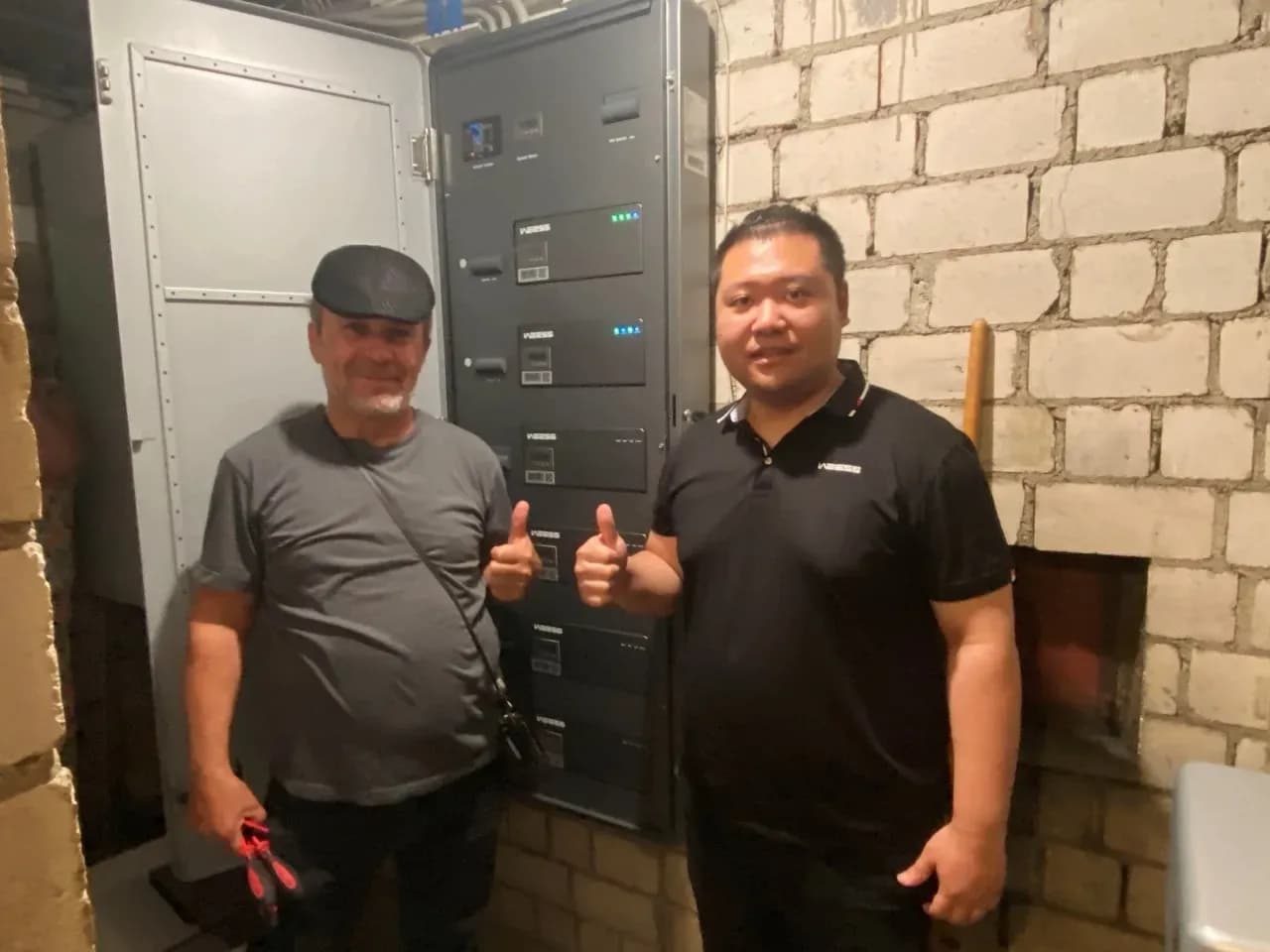 Kunde und Techniker präsentieren installierten WEESS Powertower Energiespeicher im Technikraum