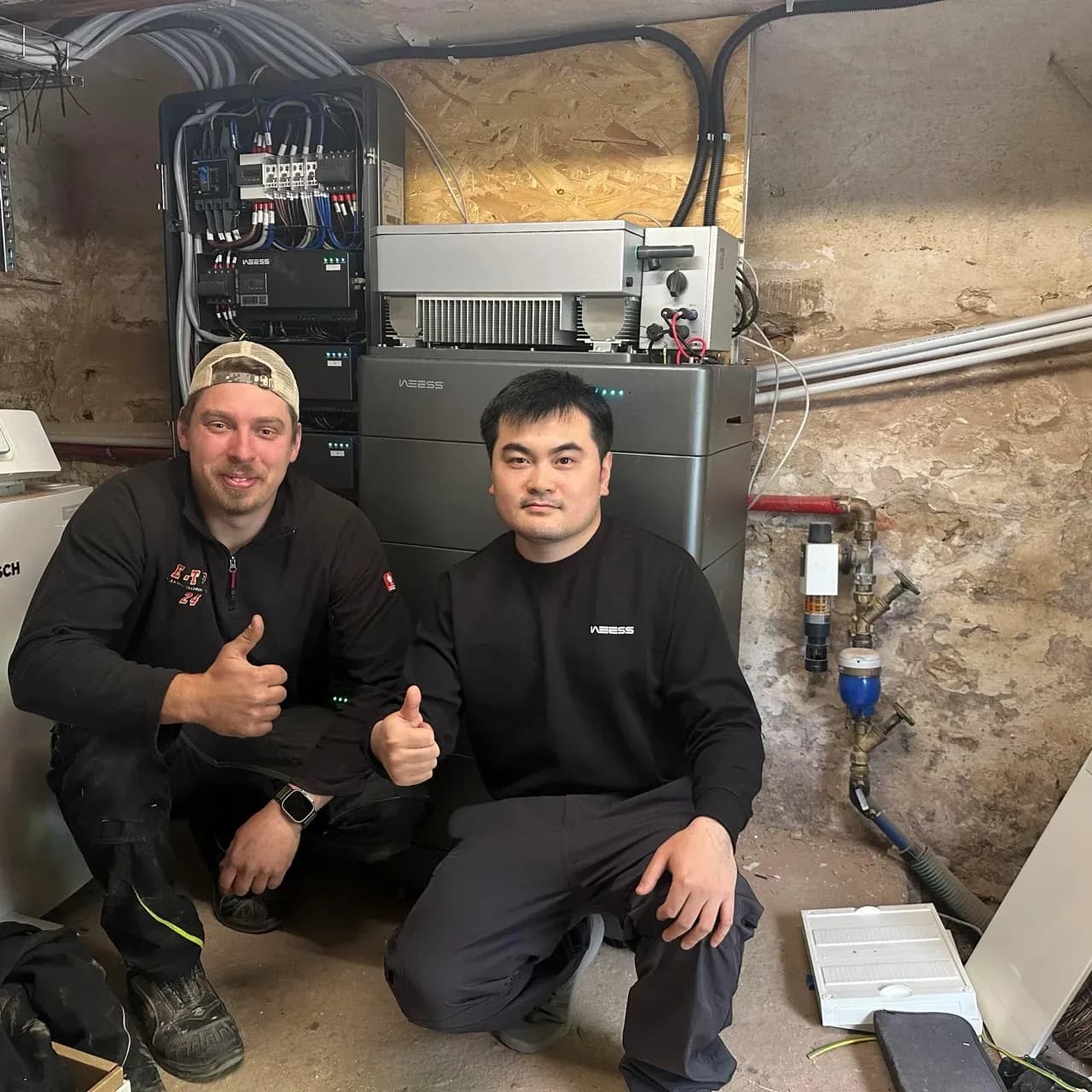 Techniker vor installiertem WEESS Batteriespeicher und Energieverteilungssystem im Keller