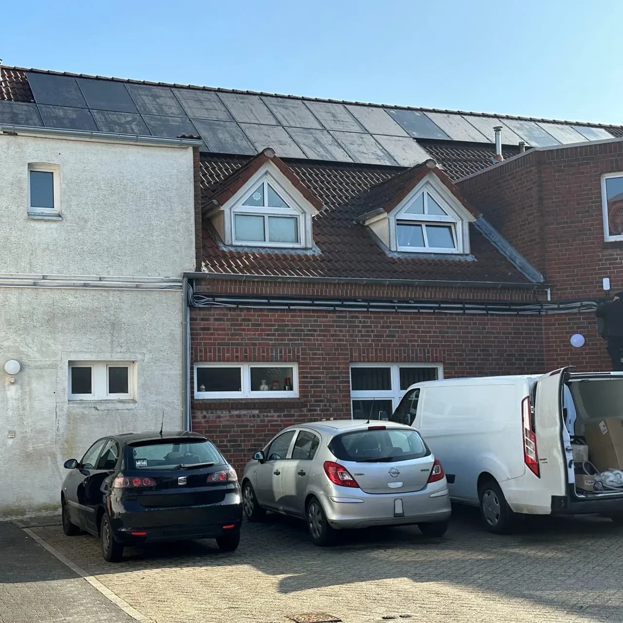 Mehrfamilienhaus mit Photovoltaikanlage auf dem Dach und Parkplätzen davor